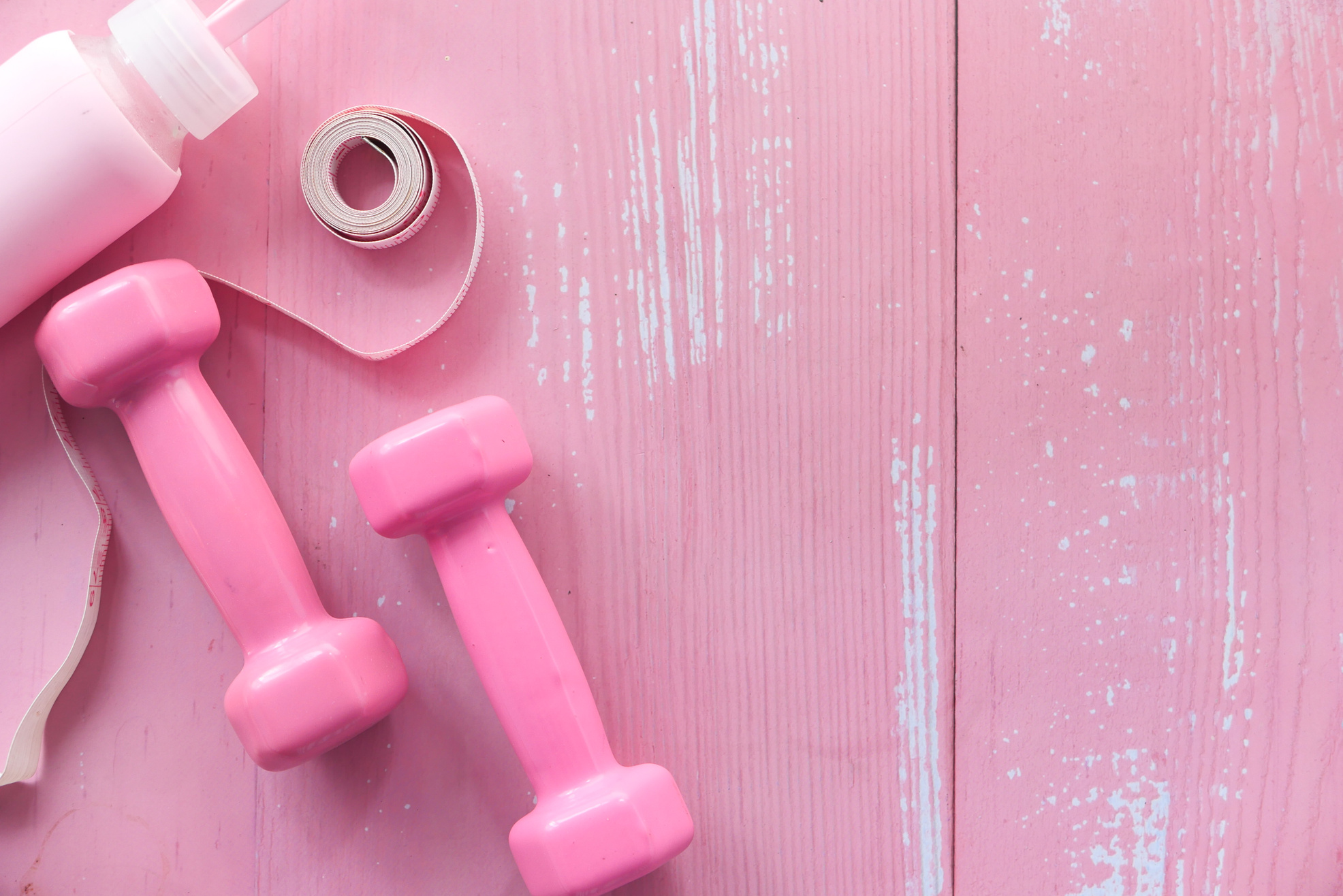 Pink Color Dumbbell, Measurement Tape and Water Bottle on Table
